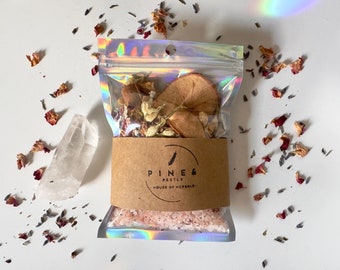 May include: A clear plastic bag filled with dried fruit, flowers, and herbs. The bag is labeled "Pine & Pestle, House of Herbals".