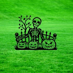 May include: Black metal silhouette of a skeleton sitting on a fence with three jack-o'-lantern pumpkins. The skeleton is holding a pumpkin in its left hand. The fence has a small tree behind it.