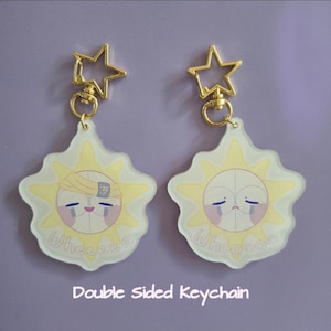 Puede incluir: Dos llaveros de doble cara con un diseño de sol, una cara triste, rayos amarillos y las palabras "Wheeeee" y "Whooooo". Cada llavero tiene un cierre dorado en forma de estrella.