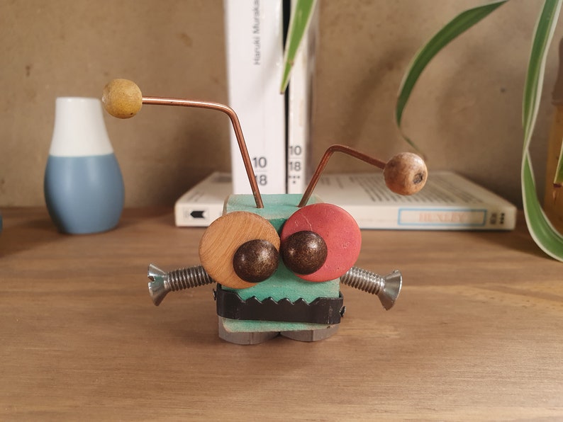 Pequeña criatura robot hecha de madera y metal reciclados imagen 1