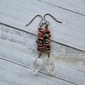 May include: A pair of long, dangling earrings with a brown wire and a cluster of small, multi-colored stones. The stones are topped with a clear quartz crystal.