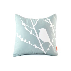 May include: A light blue throw pillow with a white silhouette of a bird on a branch. The pillow is made of a soft, comfortable fabric and is perfect for adding a touch of nature to any room.
