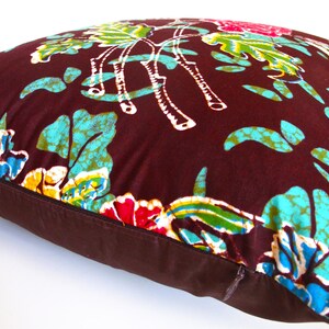 May include: A brown pillow with a floral pattern in shades of blue, green, yellow, and pink. The pillow has a brown zipper.