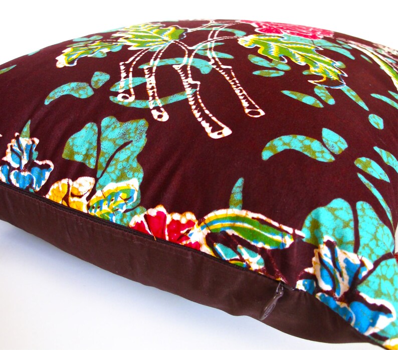 May include: A brown pillow with a floral pattern in shades of blue, green, yellow, and pink. The pillow has a brown zipper.