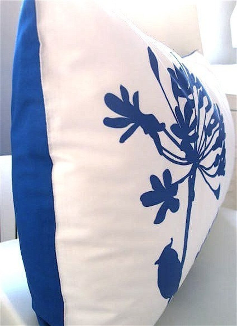 May include: White pillow with a blue floral design. The pillow has a blue border.