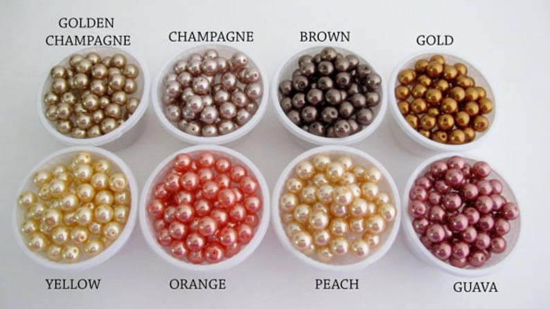 Puede incluir: Un surtido de cuentas de perlas en varios colores, incluyendo champ&aacute;n dorado, champ&aacute;n, marr&oacute;n, oro, amarillo, naranja, melocot&oacute;n y guayaba. Cada color se muestra en un peque&ntilde;o recipiente blanco con su nombre.