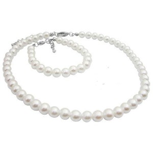 Puede incluir: Un conjunto de collar y pulsera de perlas blancas. El collar y la pulsera presentan perlas redondas y brillantes, unidas por un cierre plateado. Las perlas var&iacute;an ligeramente de tama&ntilde;o, creando un conjunto de joyer&iacute;a cl&aacute;sico.