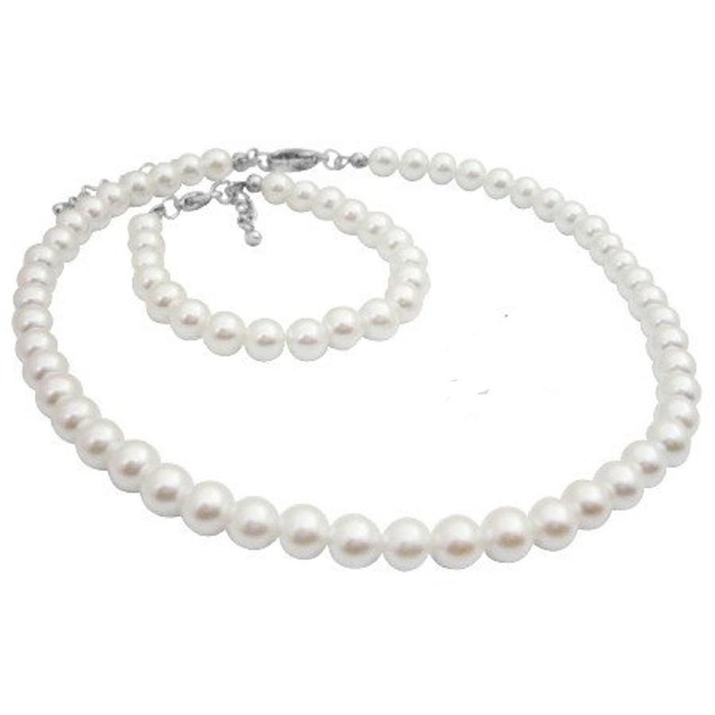Puede incluir: Un conjunto de collar y pulsera de perlas blancas. El collar y la pulsera presentan perlas redondas y brillantes, unidas por un cierre plateado. Las perlas var&iacute;an ligeramente de tama&ntilde;o, creando un conjunto de joyer&iacute;a cl&aacute;sico.