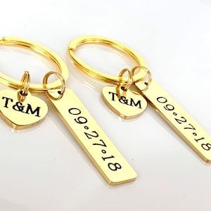 May include: Two gold keychains with matching heart-shaped and rectangular tags. The heart tags have the initials "T&M", and the rectangular tags display the date "09.27.18".