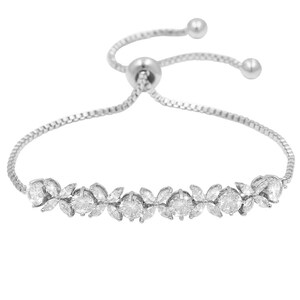 K&ouml;nnte beinhalten: Ein silberfarbenes Armband mit einem zarten floralen Design. Das Armband hat einen Schiebeverschluss zur Gr&ouml;&szlig;enanpassung und ist mit funkelnden, klaren Edelsteinen verziert. Die Blumenanordnung umfasst runde und marquisef&ouml;rmige Steine.