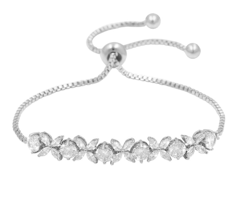 K&ouml;nnte beinhalten: Ein silberfarbenes Armband mit einem zarten floralen Design. Das Armband hat einen Schiebeverschluss zur Gr&ouml;&szlig;enanpassung und ist mit funkelnden, klaren Edelsteinen verziert. Die Blumenanordnung umfasst runde und marquisef&ouml;rmige Steine.