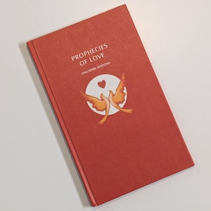 May include: A rectangular book with a textured terracotta red cover. The front features the white text "PROPHECIES OF LOVE" and "HALLMARK EDITIONS" above a white circular graphic containing two orange birds and a small red heart icon.