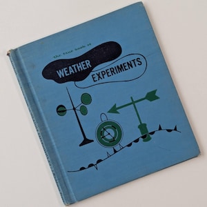 May include: A light blue hardcover book titled The True Book of Weather Experiments. The cover features a dark blue cloud shape with white text, alongside green illustrations of a wind vane, an anemometer, and a barometer on a wavy line.