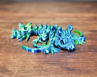 May include: A blue and green 3D printed lizard figurine with a spiky back and a textured surface.