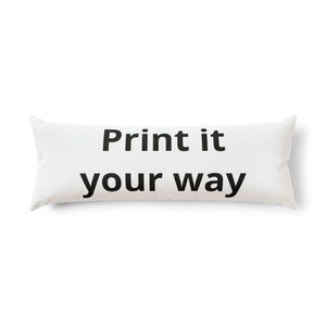 Puede incluir: Una almohada corporal rectangular de color blanco con el texto negro Print it your way centrado en la parte frontal. La almohada tiene una superficie de tela lisa y esquinas puntiagudas en ambos extremos, manteniendo un diseño limpio.