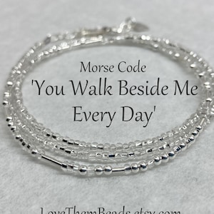 May include: Silver beaded bracelet with the message 'You Walk Beside Me Every Day' in Morse code.