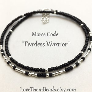 May include: Black and silver beaded bracelet with a Morse code message that reads "Fearless Warrior".