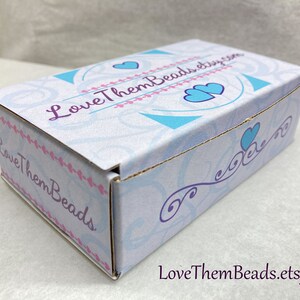 May include: A white cardboard box with a blue and white design featuring hearts and the text "LoveThemBeads.etsy.com".