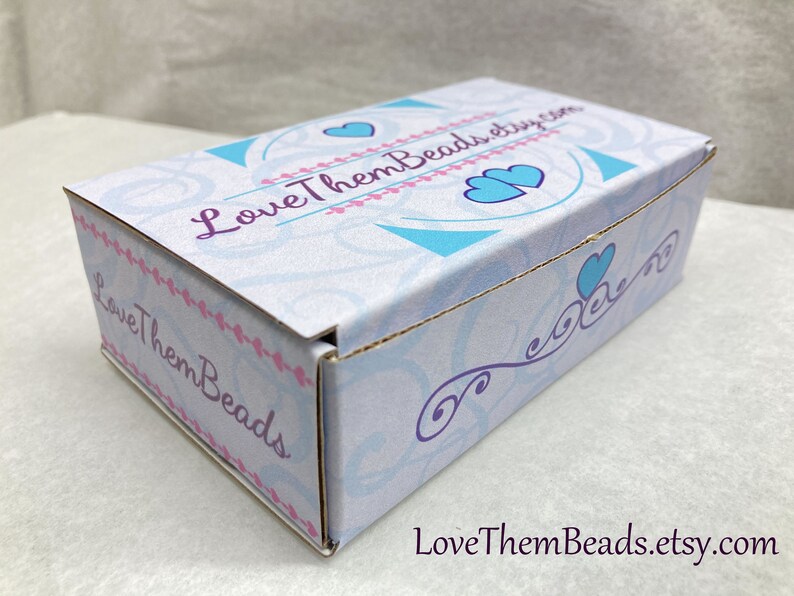 May include: A white cardboard box with a blue and white design featuring hearts and the text "LoveThemBeads.etsy.com".