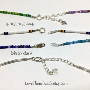 May include: Four beaded necklaces with different colored beads and clasps. The top two necklaces have spring ring clasps, and the bottom two necklaces have lobster clasps. The text "LoveThemBeads.etsy.com" is visible at the bottom of the image.