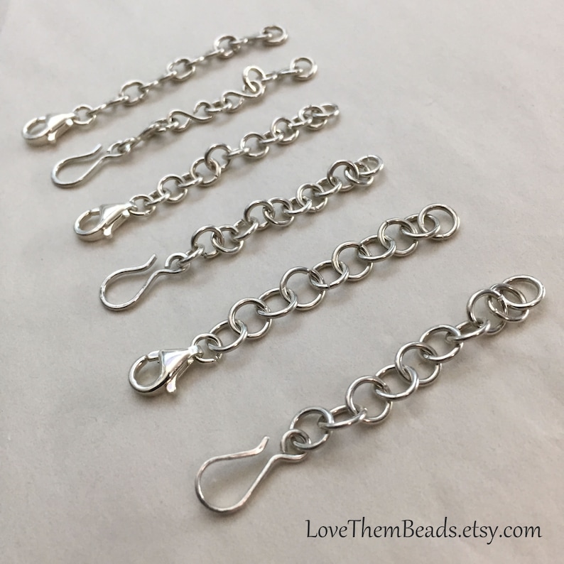 May include: Five silver chain extenders of varying lengths, each with a lobster clasp on one end and a jump ring on the other.