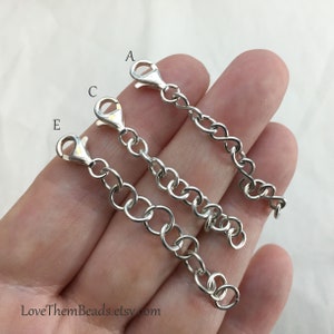 May include: Three silver extender chains with lobster claw clasps. The chains are labeled A, C, and E. The chains are different lengths.