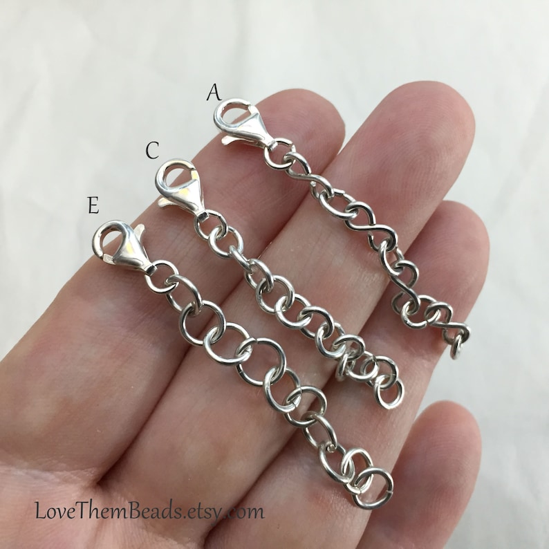 May include: Three silver extender chains with lobster claw clasps. The chains are labeled A, C, and E. The chains are different lengths.