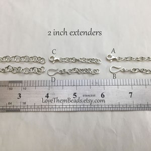 May include: Six silver chain extenders, each measuring 2 inches in length. The extenders are labeled A through F and are displayed on a ruler.