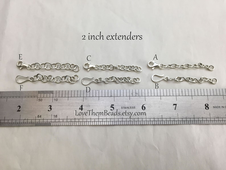 May include: Six silver chain extenders, each measuring 2 inches in length. The extenders are labeled A through F and are displayed on a ruler.