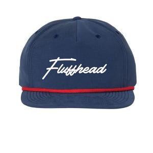 Könnte beinhalten: Marineblaue Baseballkappe mit dem Wort "Fluffhead" in weißer Schrift auf der Vorderseite. Der Schirm hat einen roten Akzent. Die Kappe hat ein klassisches Sechs-Panel-Design.