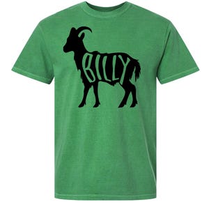 Puede incluir: Camiseta verde con una silueta negra de cabra y la palabra "BILLY" en blanco. La camiseta tiene cuello redondo y mangas cortas. Prenda casual.