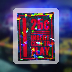 May include: A holographic sticker with a rectangular design. The sticker features the text "25¢" in red, above "INSERT COIN TO PLAY" also in red. The background is a mosaic of colorful, reflective shapes, with a white border.