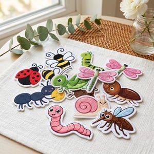 May include: A collection of embroidered insect and garden creature patches including a red ladybug, yellow and black bee, green grasshopper, pink dragonfly, brown beetle, pink snail, pink worm, black ant, and a brown mosquito with blue wings.