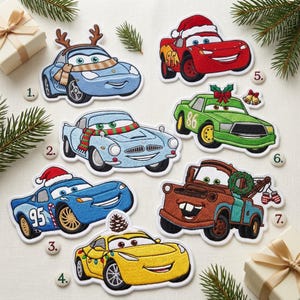 May include: A collection of seven embroidered patches featuring characters from the movie Cars, including a red race car with a Santa hat, a blue car with reindeer antlers, a green car with a bow, and a brown tow truck with a wreath.
