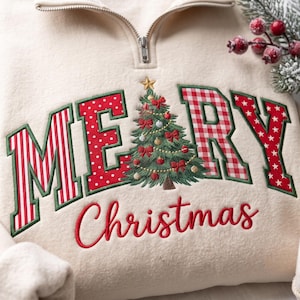 May include: A cream-colored quarter-zip sweatshirt featuring the embroidered text MERRY CHRISTMAS. The letter E is replaced by a green Christmas tree with red bows and ornaments. The letters M, R, and Y feature red and white patterns.