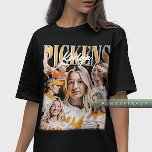 Może przedstawiać: Czarny t-shirt z kolażem zdjęć i napisem "Pickens Karley" złotymi literami. Zdjęcia przedstawiają zawodniczkę softballu w pomarańczowych i białych strojach. Widoczny jest tekst "PUNGDEVSHOP".
