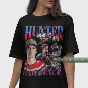 May include: Black t-shirt featuring a collage of images with the name "HUNTER LAWRENCE" in red and blue text. The design includes portraits of a man in racing gear, a motorcycle, and the number 96.