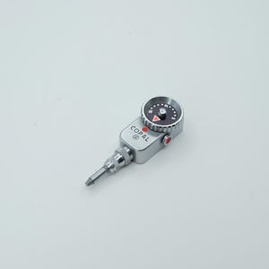 May include: A silver-colored Copal mechanical timer featuring a circular dial with black background, white numbering from 5 to 15, and a red triangular indicator. The device has a metallic body, a knurled adjustment knob, and a protruding metal tip.