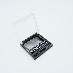 May include: A white ceramic mug with a black handle and the text "But first, coffee" in a handwritten style. The mug is on a white surface. The mug is approximately 4 inches tall.