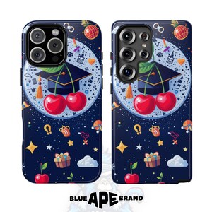 May include: Two phone cases with a dark blue background featuring a graduation cap with cherries, stars, and other decorative elements. The cases have a glossy finish and the brand name "BLUE APE BRAND" is at the bottom.
