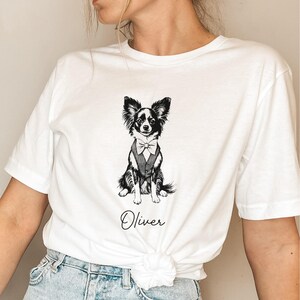 May include: White t-shirt featuring a black and white illustration of a dog wearing a bow tie. The text "Oliver" is printed below the dog.