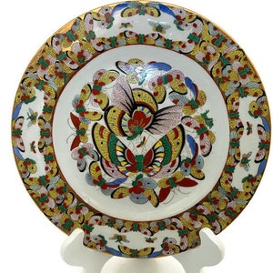 May include: A white porcelain plate with a gold rim and a colourful butterfly design. The butterflies are painted in shades of red, blue, yellow, and green. The plate is decorated with a border of gold butterflies.