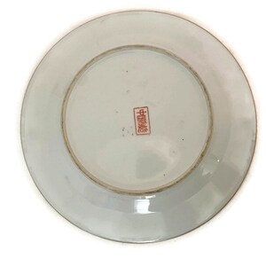 May include: White porcelain plate with a red Chinese character mark on the bottom. The plate has a raised rim and a smooth surface.