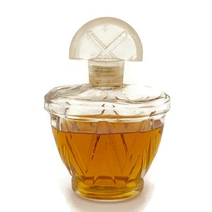 May include: A clear glass bottle with a faceted design, filled with a golden liquid. The bottle has a clear plastic stopper with a cross-shaped design.