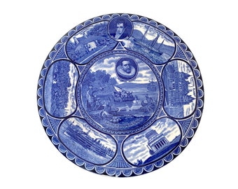 Puede incluir: Plato de cerámica azul y blanco con un diseño decorativo que representa escenas de la historia de la ciudad de Nueva York. Las escenas incluyen el desembarco de Hendrick Hudson, los primeros colonos holandeses, la construcción de la primera iglesia y la construcción del primer ayuntamiento. El plato es un hermoso ejemplo de arte decorativo vintage.