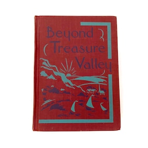 May include: A red hardcover book titled Beyond Treasure Valley with light blue and dark purple graphic illustrations on the front cover. The design features a stylized landscape with a sun, mountains, and sailboats, framed by a light blue border.