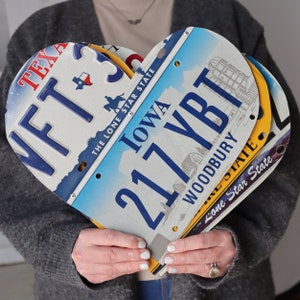 May include: A heart-shaped arrangement of three license plates from different states. The top plate is from Iowa and reads "217 YBT WOODBURY", the middle plate is from Texas and reads "WFT3", and the bottom plate is from Iowa and reads "Lone Star State".