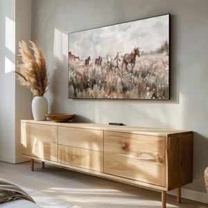 Pu&ograve; includere: Un mobile TV in legno chiaro con quattro cassetti e un dipinto di cavalli che corrono attraverso un campo appeso sopra.