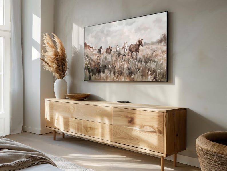 Pu&ograve; includere: Un mobile TV in legno chiaro con quattro cassetti e un dipinto di cavalli che corrono attraverso un campo appeso sopra.
