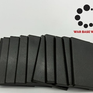 May include: A set of ten black rectangular plastic bases for miniature wargaming. The bases are arranged in a fan shape. The bases are all the same size and have a smooth, matte finish.